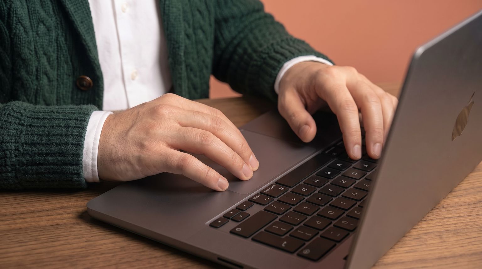 Unas manos sobre el teclado de un portátil, en un escritorio de madera
